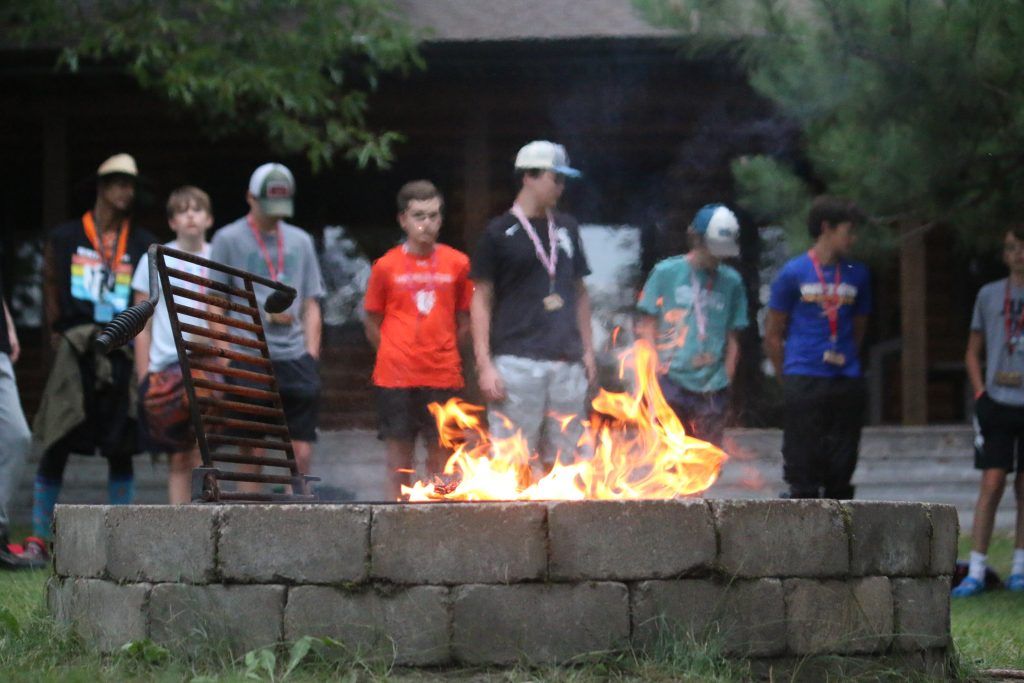 Group of teenagers sitting around a campfire forming lifelong bonds at summer camp