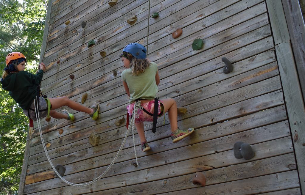 Teenager conquering a rock climbing wall at summer camp