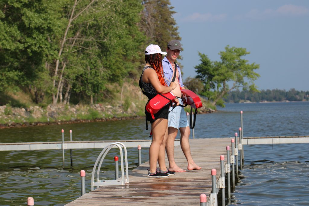A camper and counselor scanning the water and holding life guard tubes at Camp Foley