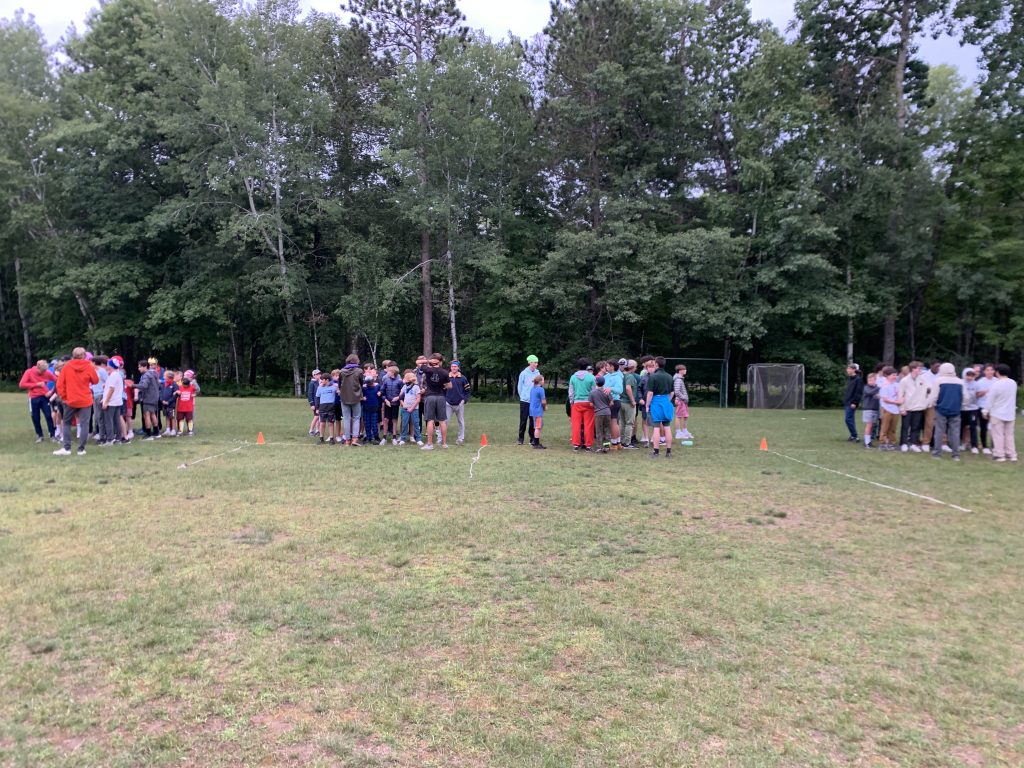 Campers standing in 4 groups in the distance on the Camp Foley soccer field 