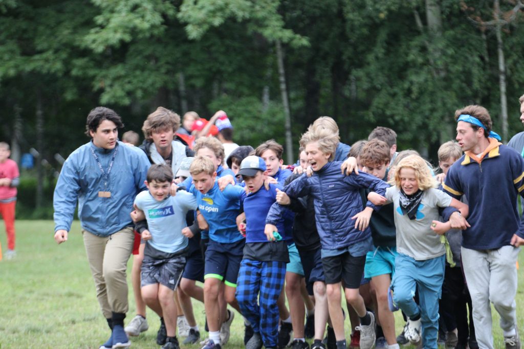 Campers on the blue team with arms linked running in a line