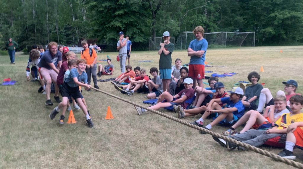 Campers playing tug of war while others watch 
