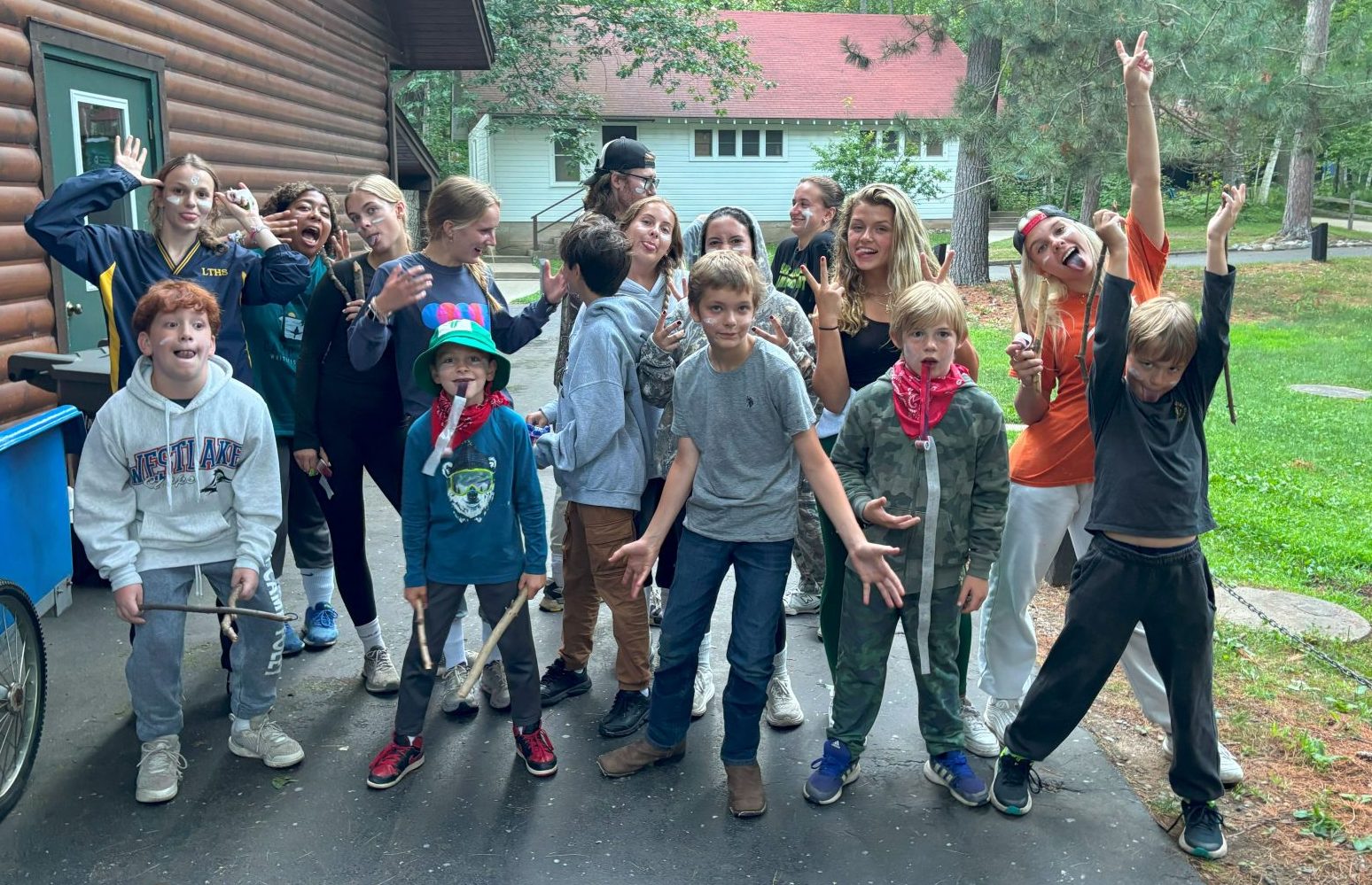 Large group of campers pose in funny movements with white face paint on their faces 