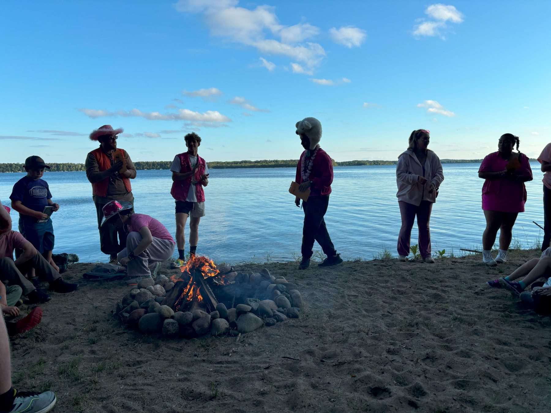 A group of people wearing pink stand on a beach 