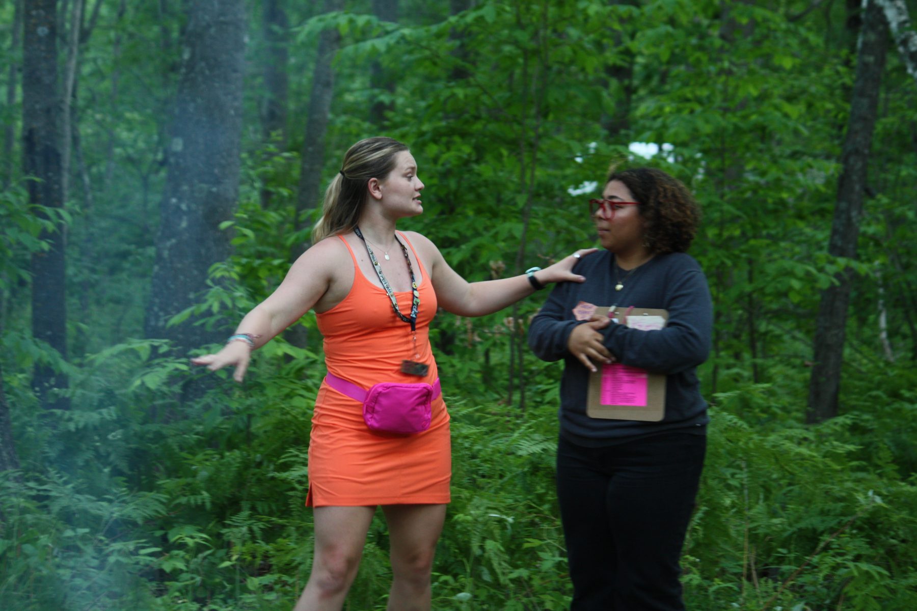 Two women stand in a forest 