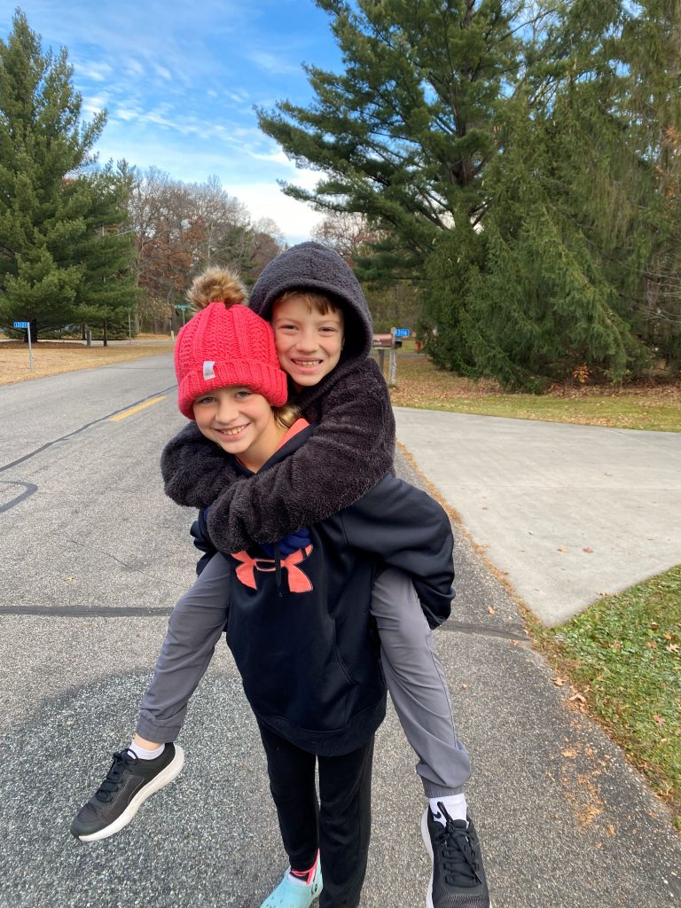 A sister gives a piggy back ride to her brother 