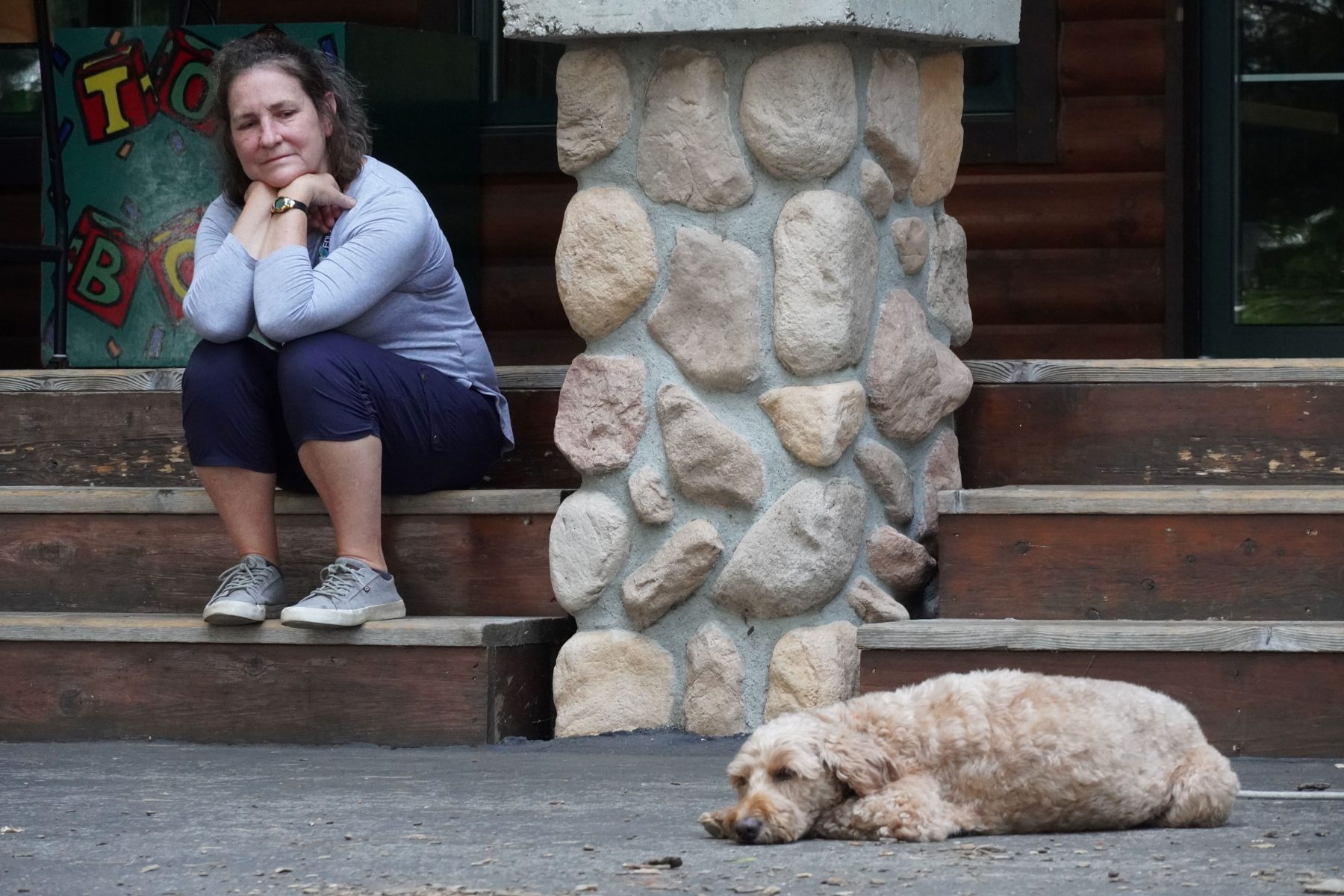 A woman smiles over at a camp dog 