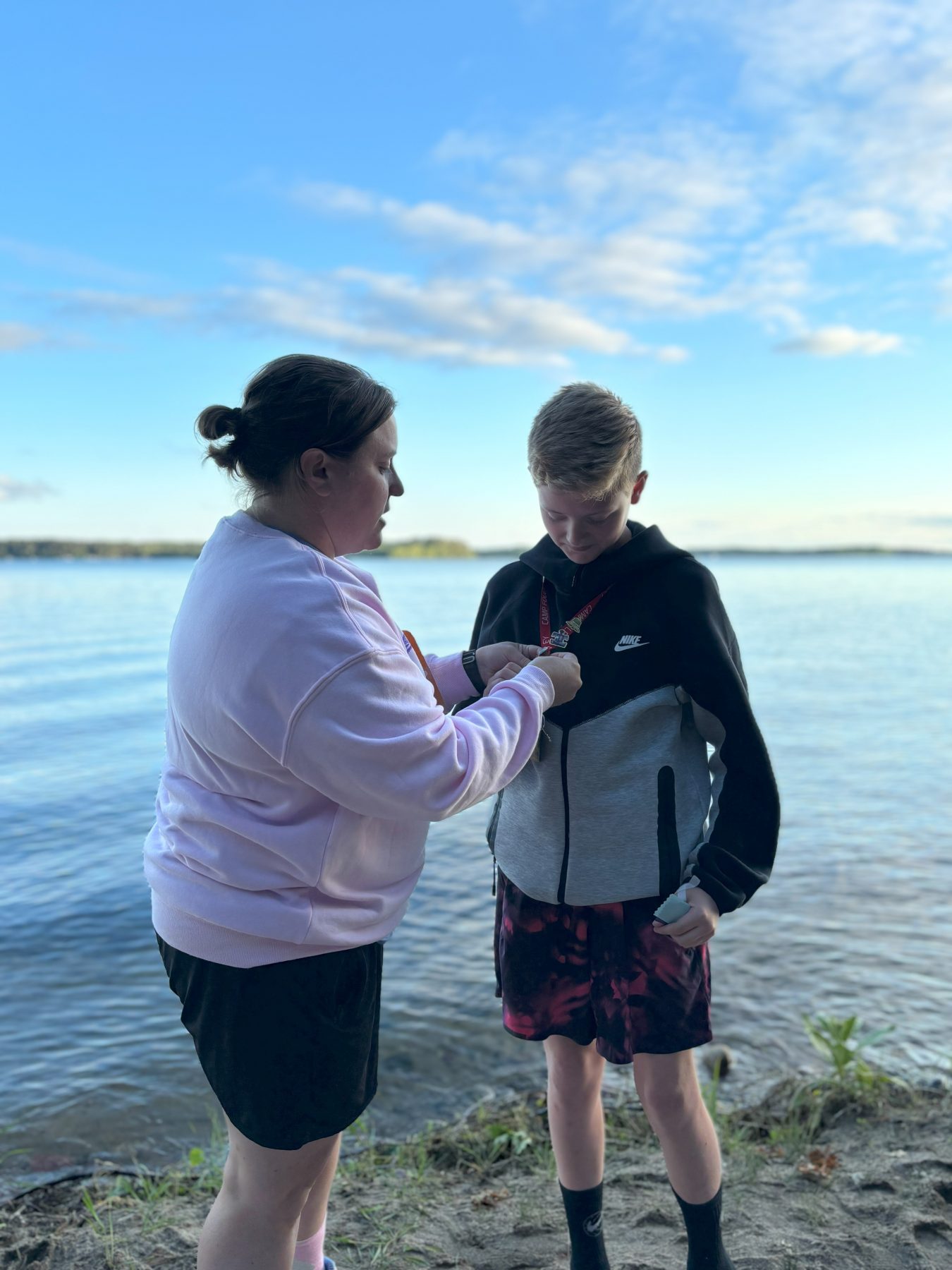 A woman pins a pin on a boy camper on the Camp Foley beach 