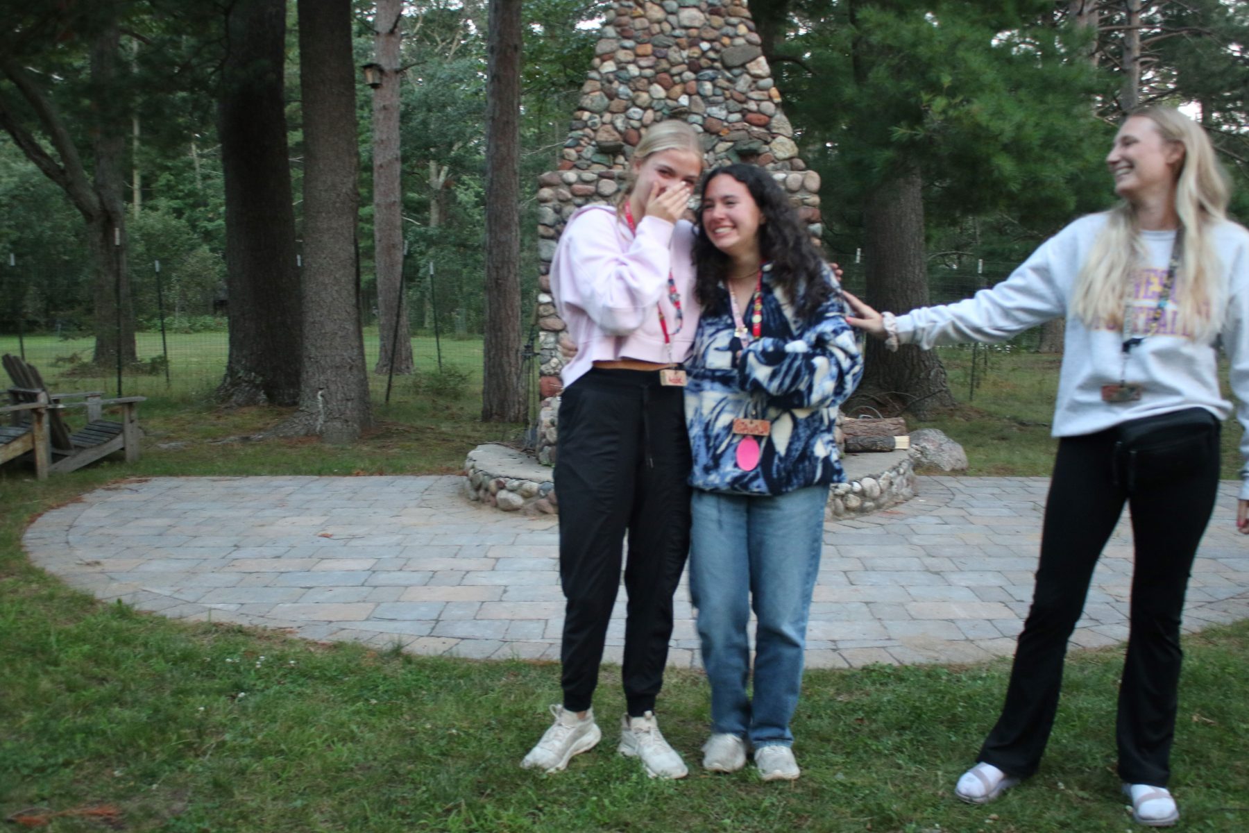 2 girl campers hug while girl counselor smiles and looks at them 