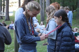 A girl pins a pin onto the lanyard of another girl camper at Camp Foley 