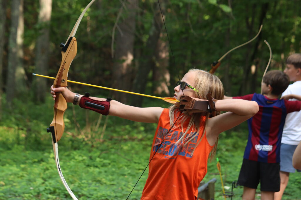 a boy Foley camper pulls a bow back to shoot an arrow at Archery 