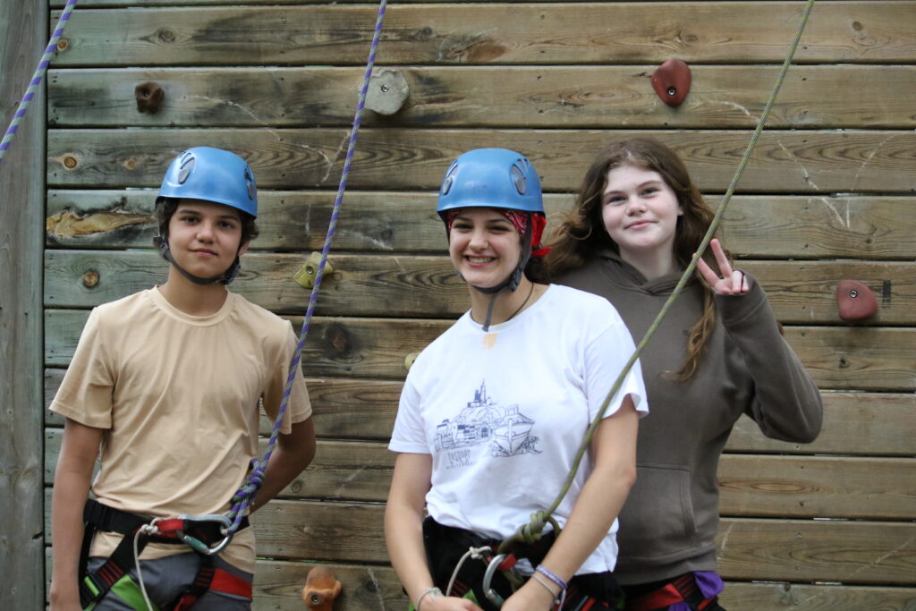 campers at camp Foley smile and pose in front of the climbing tower