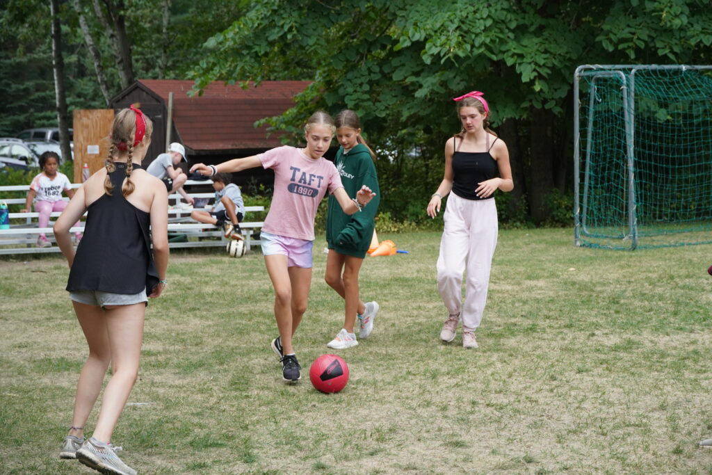 4 girls pass a soccer ball on the Camp Foley soccer field 