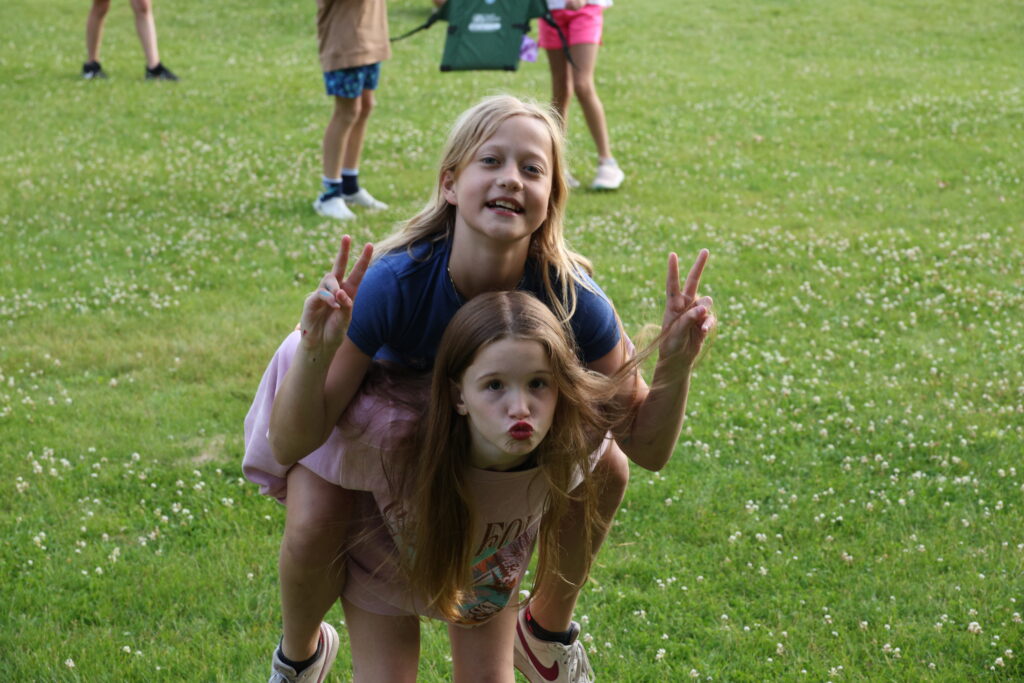 1 girl is giving a piggyback to another girl camper at Camp Foley 
