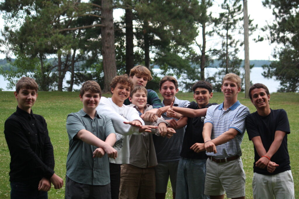 A group of Camp Foley camper boys pose together with arms outstretched and crossed. 
