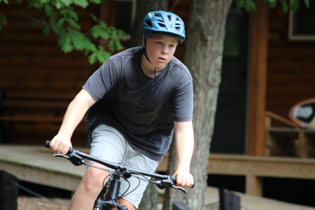 a boy camper at Camp Foley rides a bike 