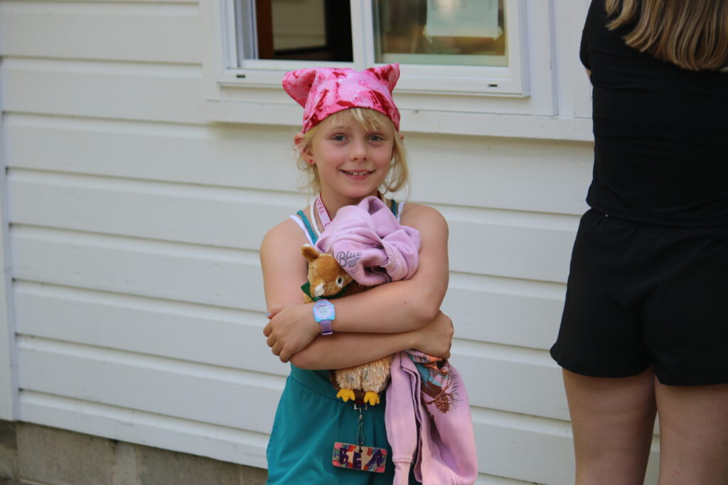 a young girl camper at Camp Foley smiles at the camera wearing a pink headband 